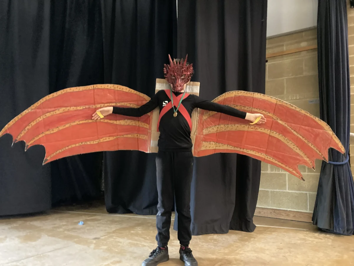 Jeune garçon portant un costume de dragon rouge en carton lors du Carnaval 2026 organisé par le Petit Club Français d'Oxfordshire.